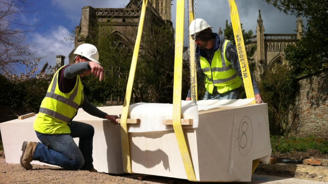 Workers guide the craned stones into position in the garden