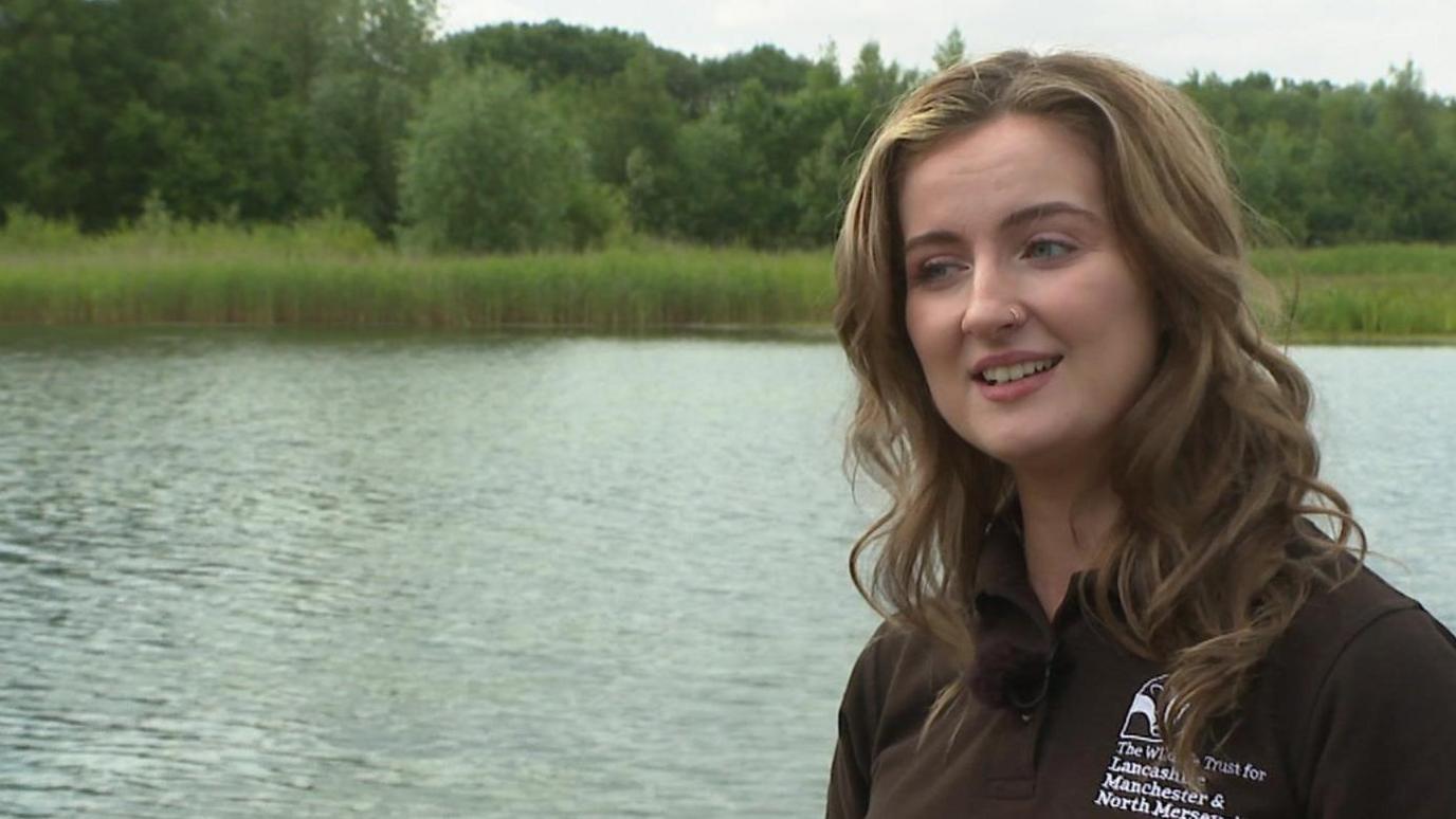 Lydia German wearing a Lancashire Wildlife Trust standing by a river