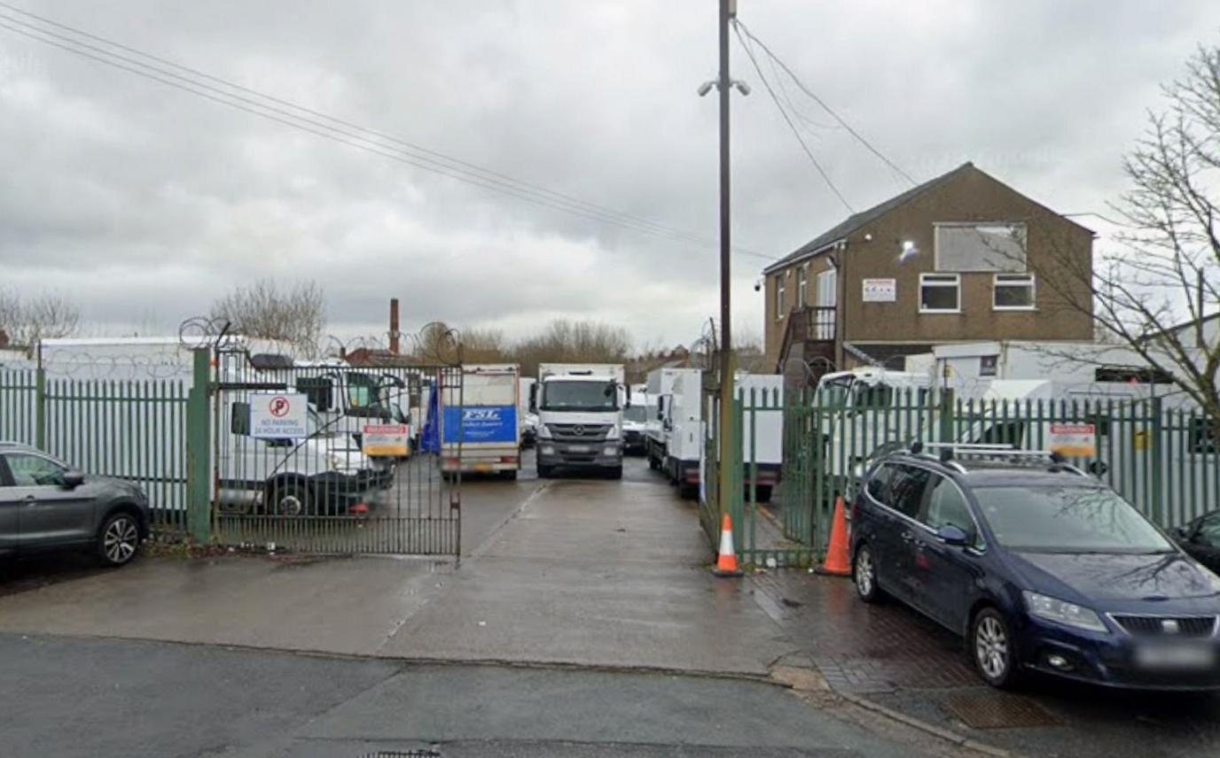 Lorries parked behind green iron gates at the proposed site