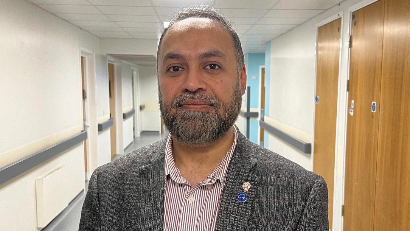 Mr Asim Sheikh standing in a hospital corridor