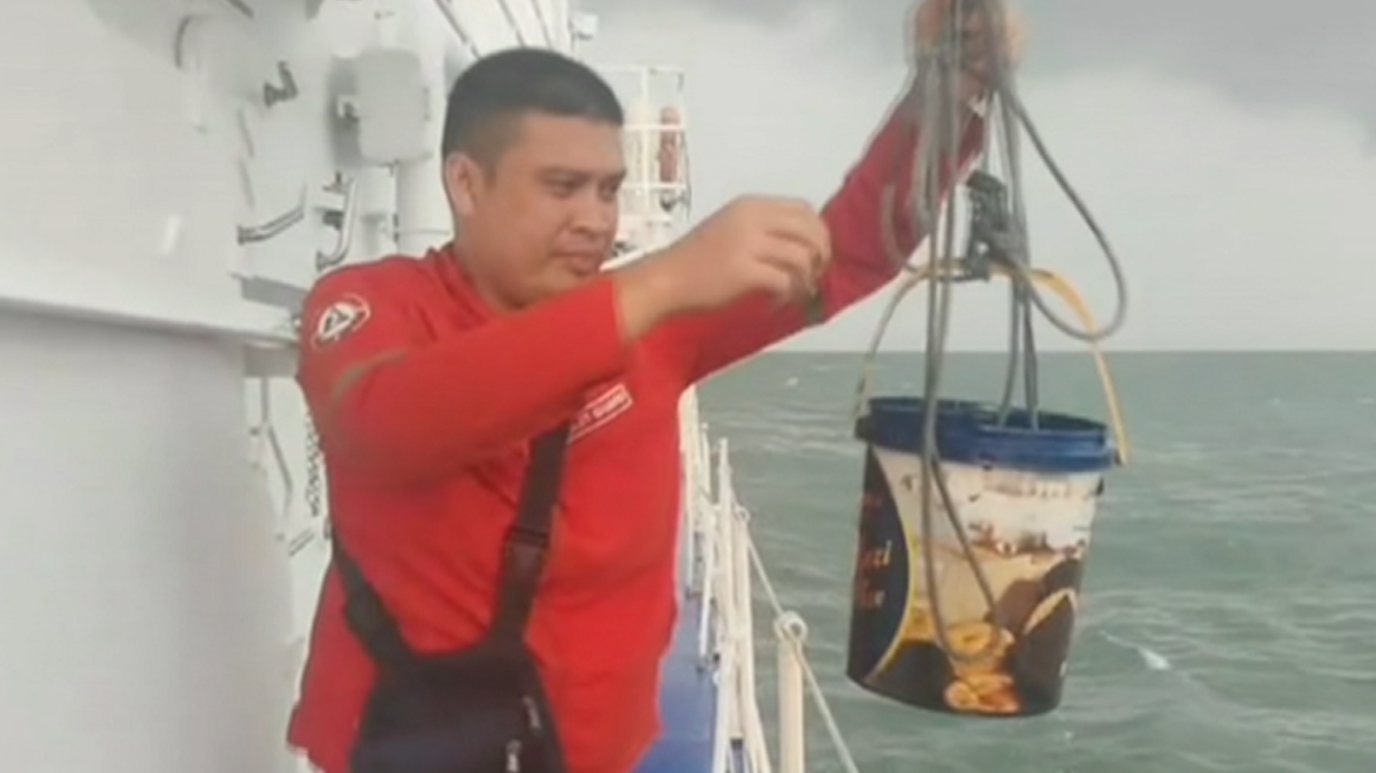 A Philippine coast guard personnel siphoning oil from the sea.