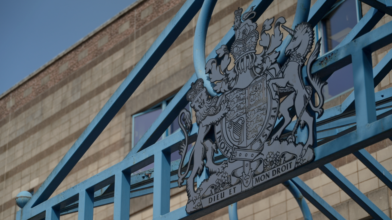 The entrance to Wolverhampton Crown Court. A blue metal frame is above the main door, with blue railings to the left of the shot.