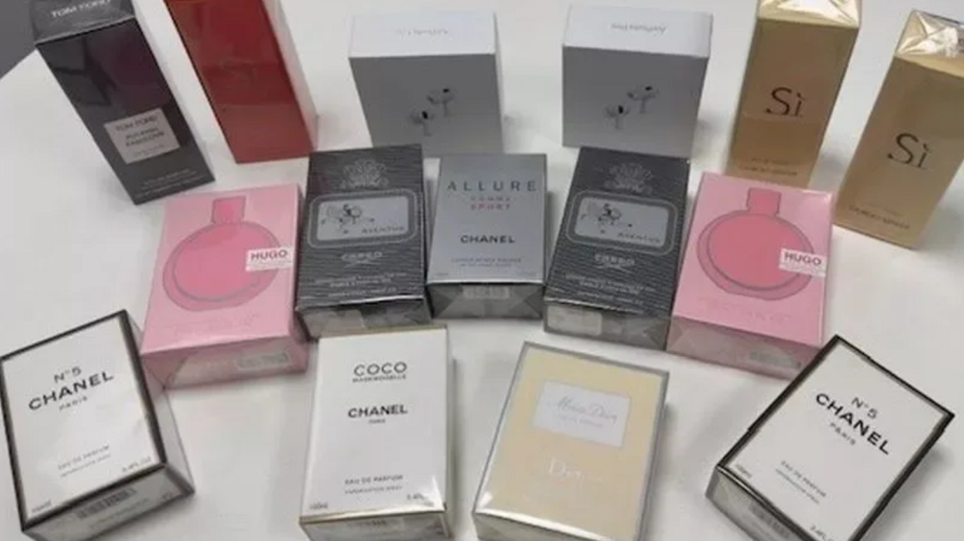 About a dozen perfume boxes looking like the real thing, spread out on a table.