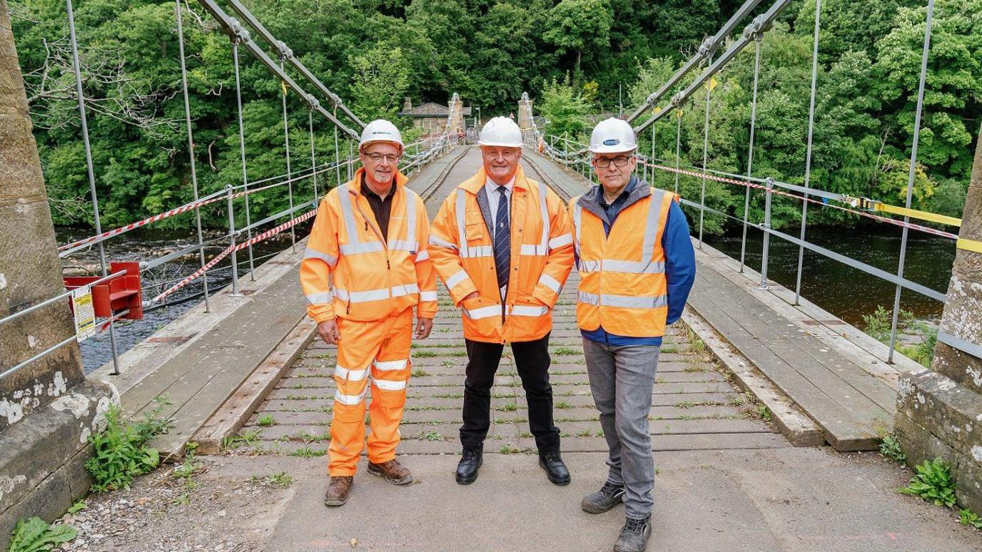 (L-R) Lee Jackson, project manager at VolkerLaser with John Shuttleworth and Alan Patrickson fromm Durham County Council. They are standing on the bridge and are wearing orange hi-vis jackets.