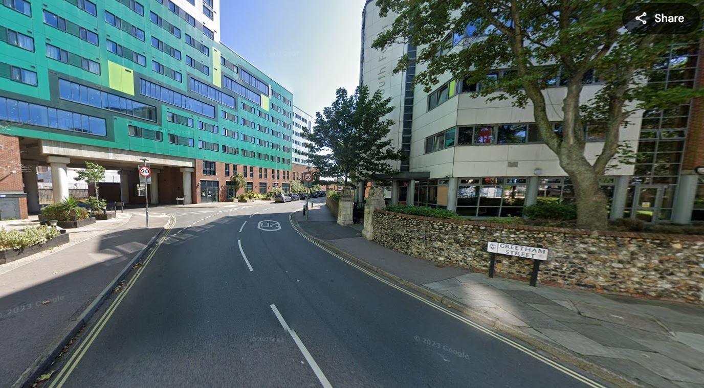 Road with blocks of flats along both sides.  It is a sunny day.