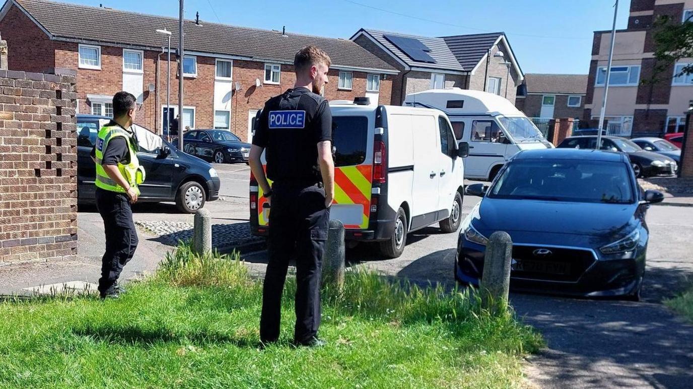 Two policemen standing near cars