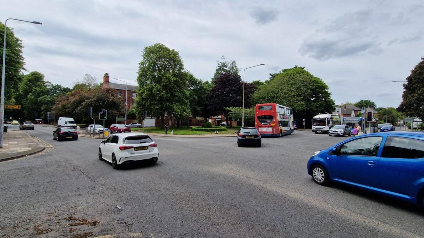 Vehicles including a blue car and bus negotiating the junction