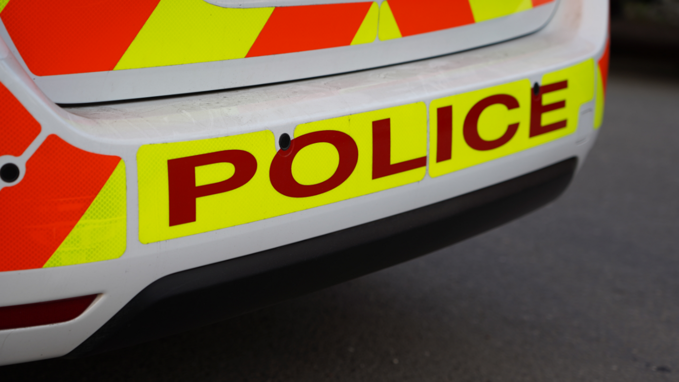 Police car. Only the rear bumper is visible, with hi-vis "Police" livery in yellow and red.