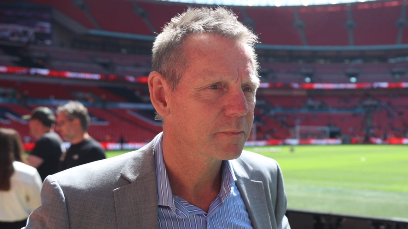 Stuart Pearce standing by the pitch at Wembley wearing a grey suit.