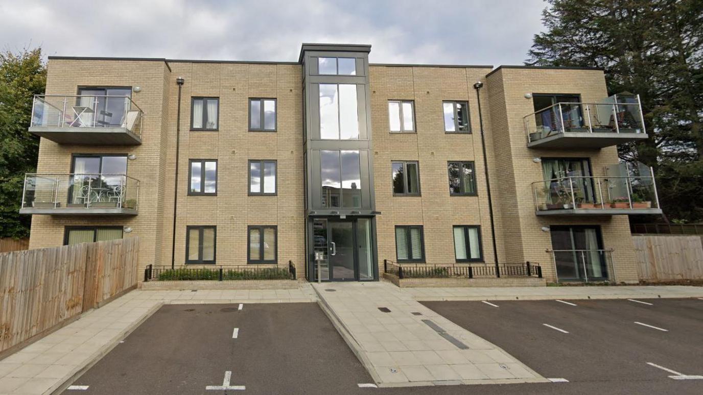 A modern apartment block over three storeys with a glass front door