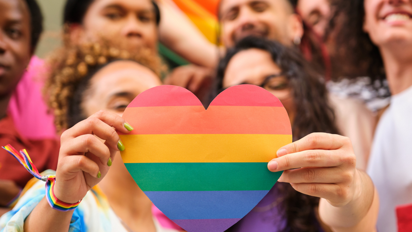 Two people hold up a heart with bright and varied colours