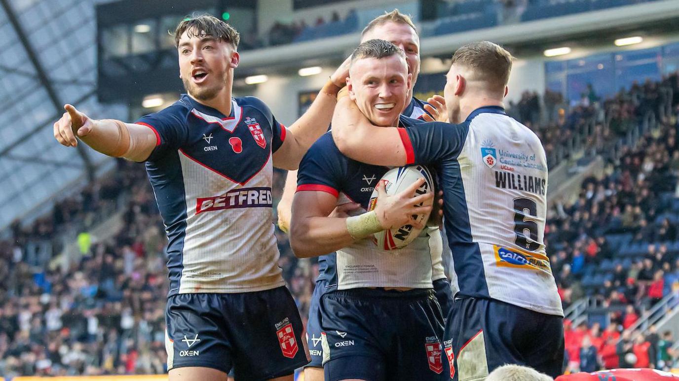 Harry Newman is mobbed by England team-mates including George Williams