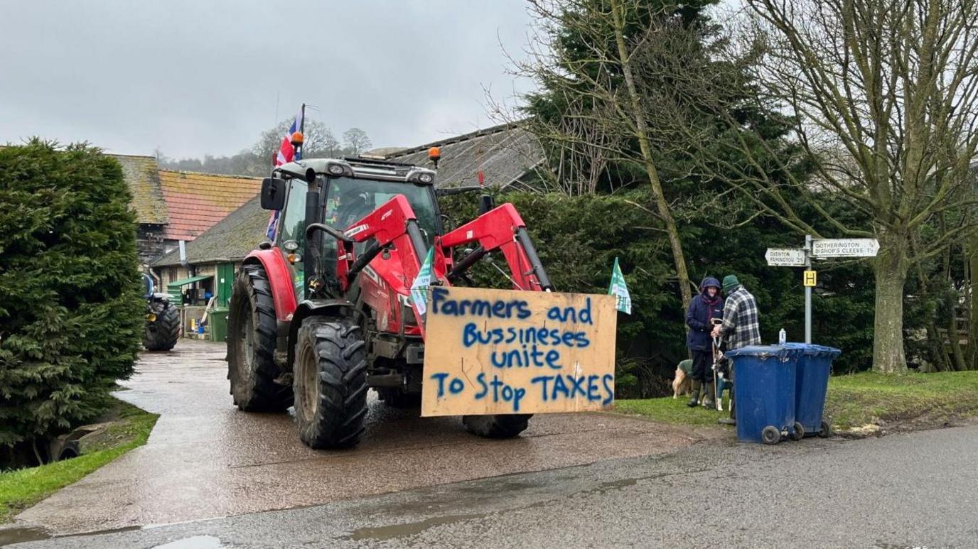 A tractor with a wooden sign on the front of it and another tractor in the background.