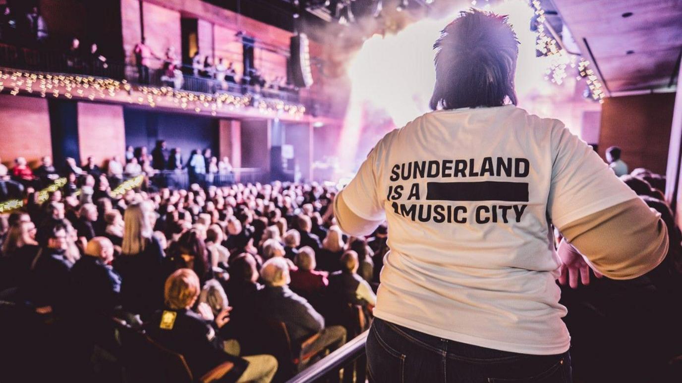 A music fan wearing a Sunderland Music City white T-shirt enjoys a sold out show at The Fire Station in Sunderland.
