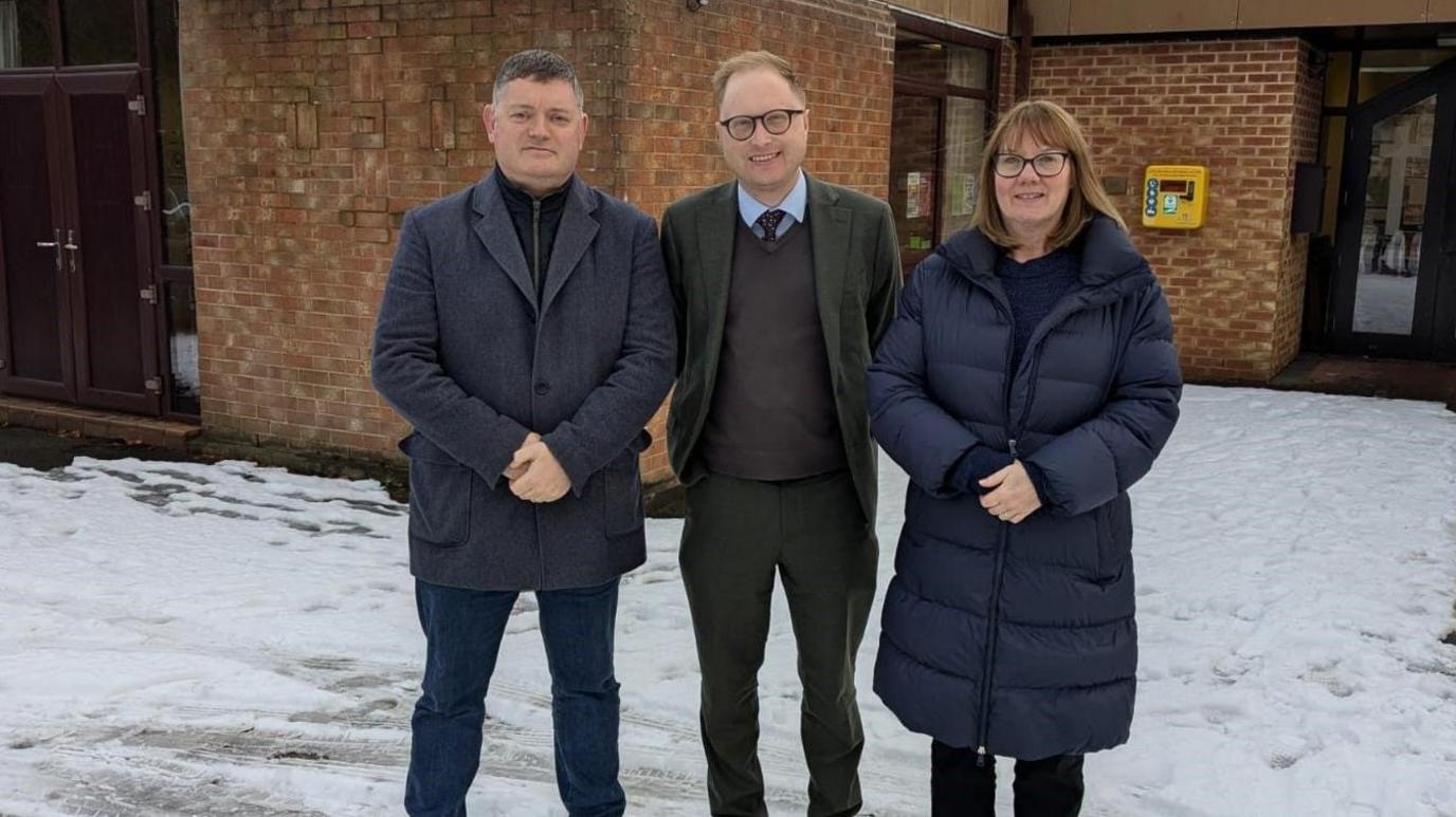 Three people stood in the snow