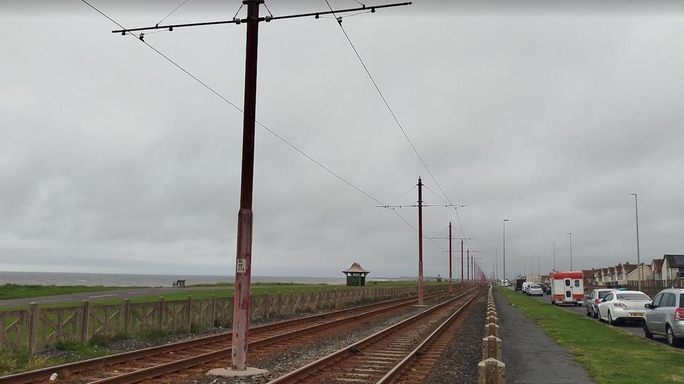 Stretch of promenade between Norbreck and Anchorsholme in Blackpool showing tramlines, parked cars and houses