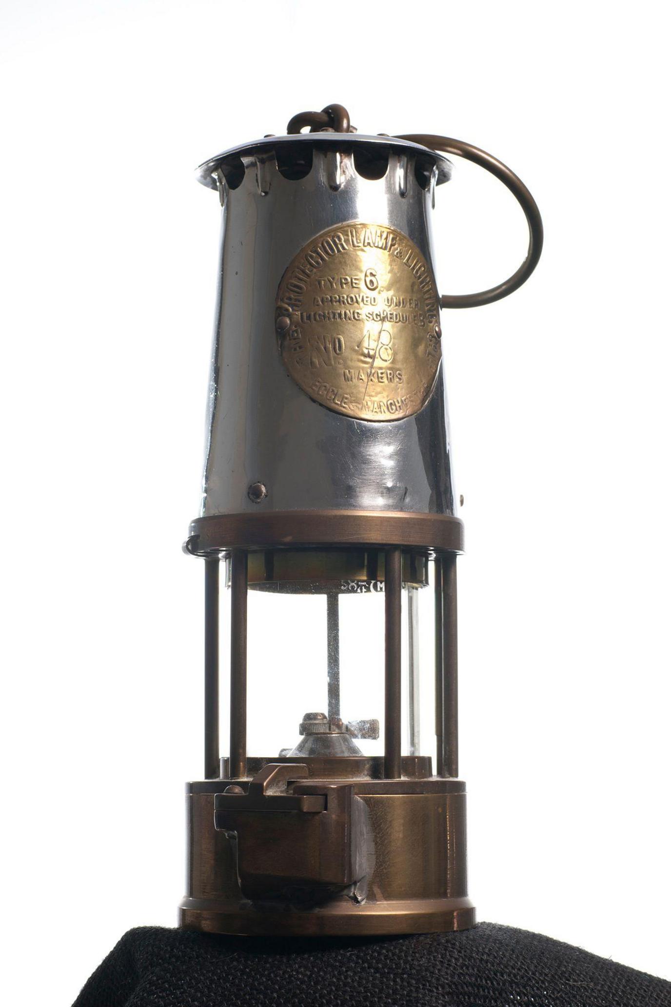 A miner's lamp - made of metal and glass with a round handle.