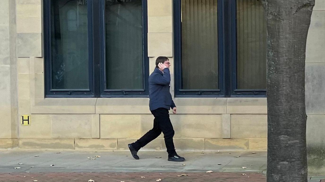 Man walking from court with hand partly covering face