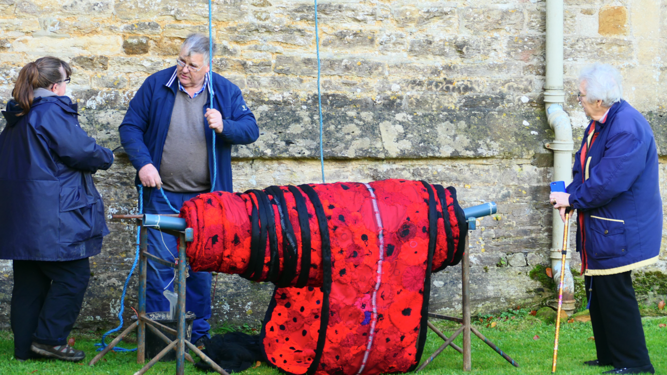 Three people around the folded poppy cascade by the church ground.