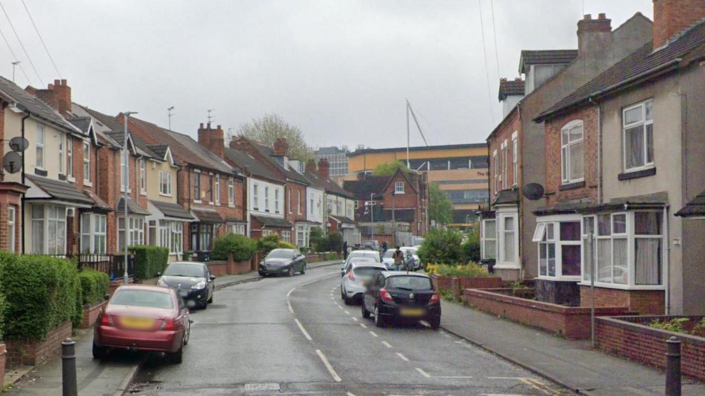 Staveley Road. It is a residential road with houses either side. Molineux Stadium is at the end. There are cars either side. 