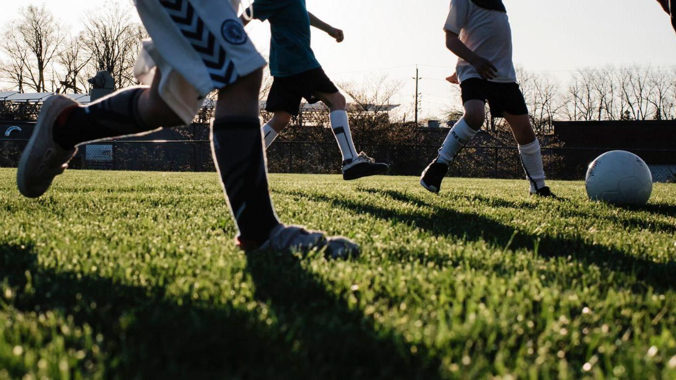 a silhouette image of three kids playing football