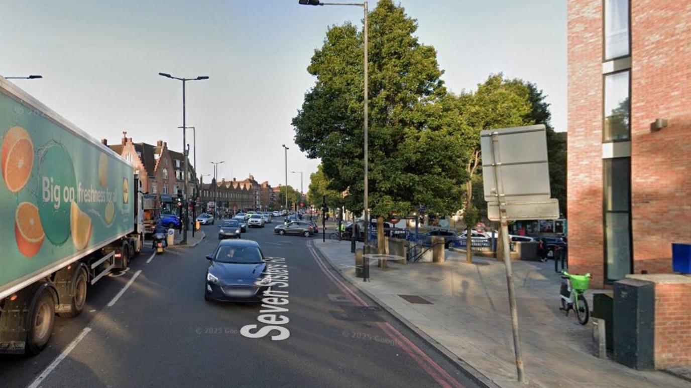 A Google Maps screen grab of the Seven Sisters Road with cars and lorries on the road and green trees on the pavement. 