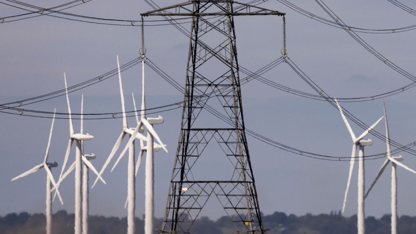 Wind turbines and power lines cut across the landscape of the Romney Marshes