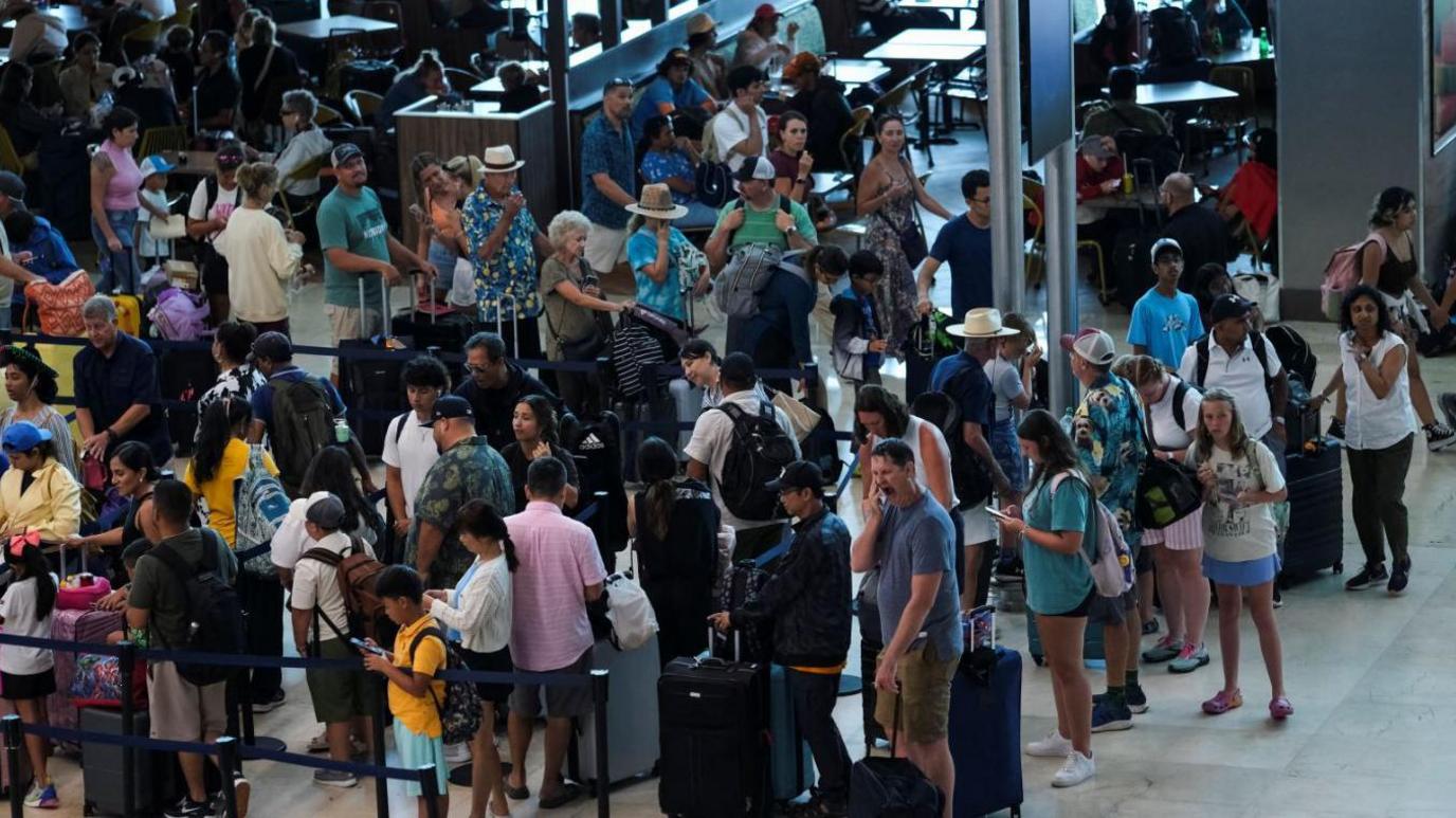 Dozens of people queue at an airport