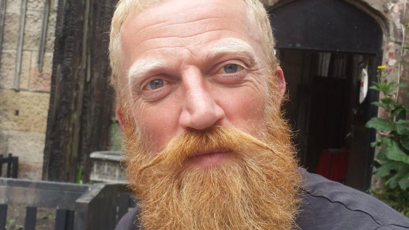 Close-up of Paul who has short cropped sandy hair and a long red beard.