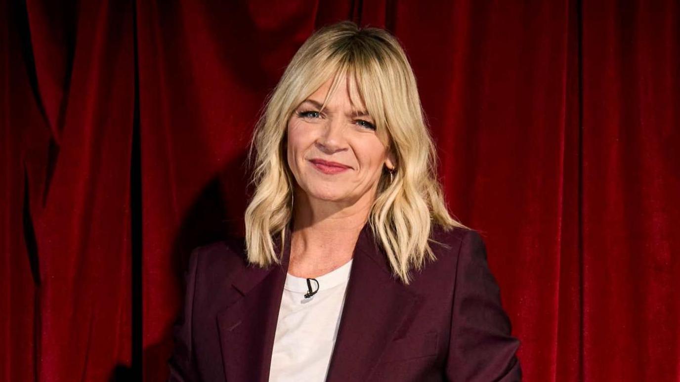 Zoe Ball wearing a white T-shirt and maroon jacket