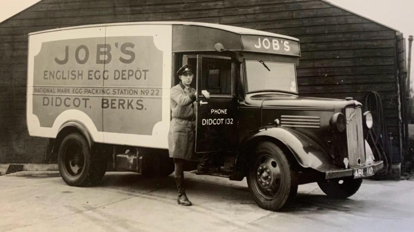 A 1940's image in sepia of Job's Dairy Didcot. A driver is in front of vehicle, looking at the camera. The side of the vehicle reads: Job's English Egg Depot. National Mark Egg Packing Station number 22. Didcot, Berks.