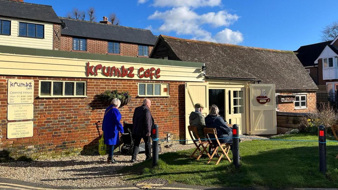 People sitting outside and walking into Krumbz Cafe