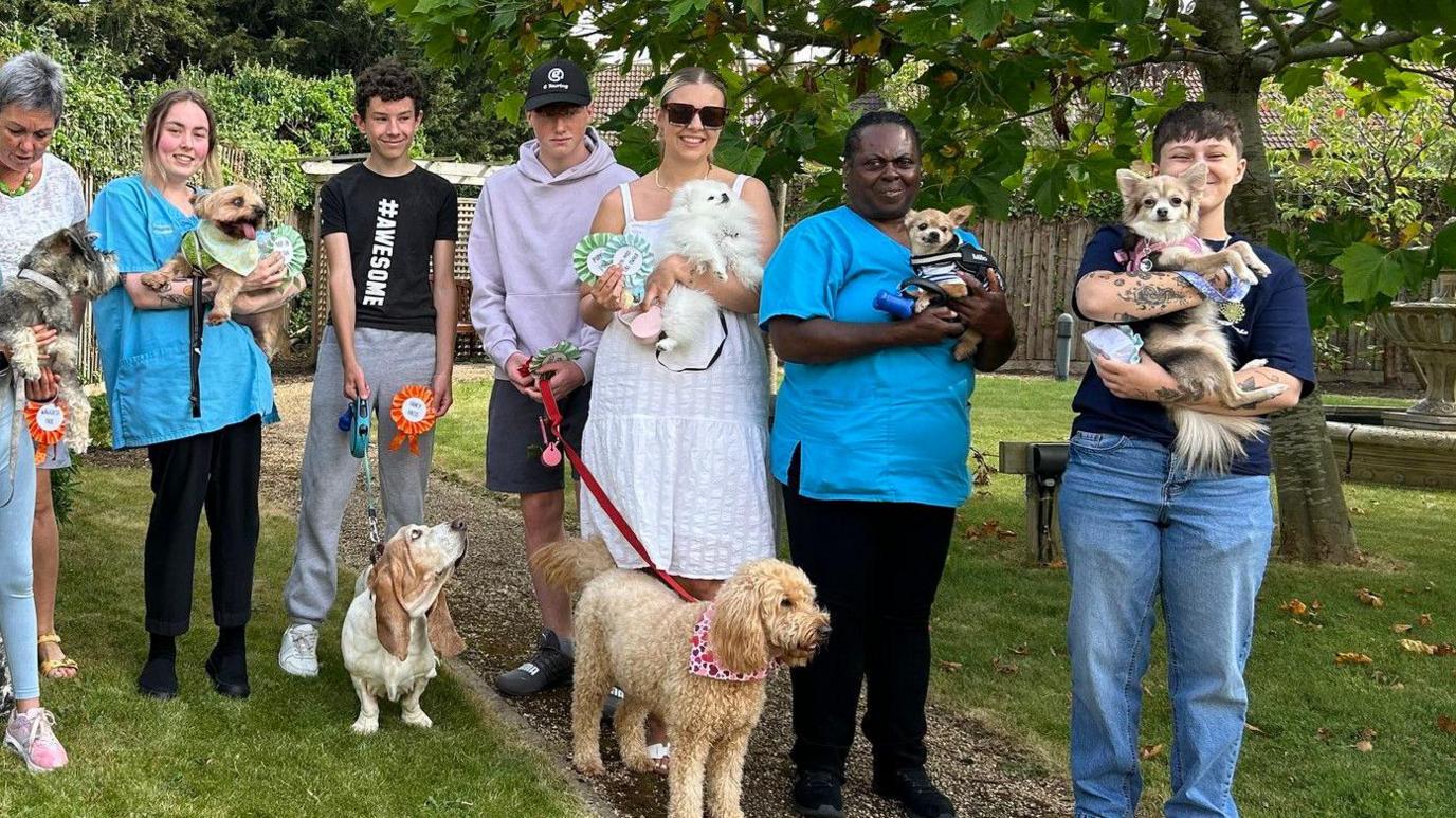 Pet owners standing with their winning pets – two white and brown dogs, one small brown dog and a large fluffy brown dog