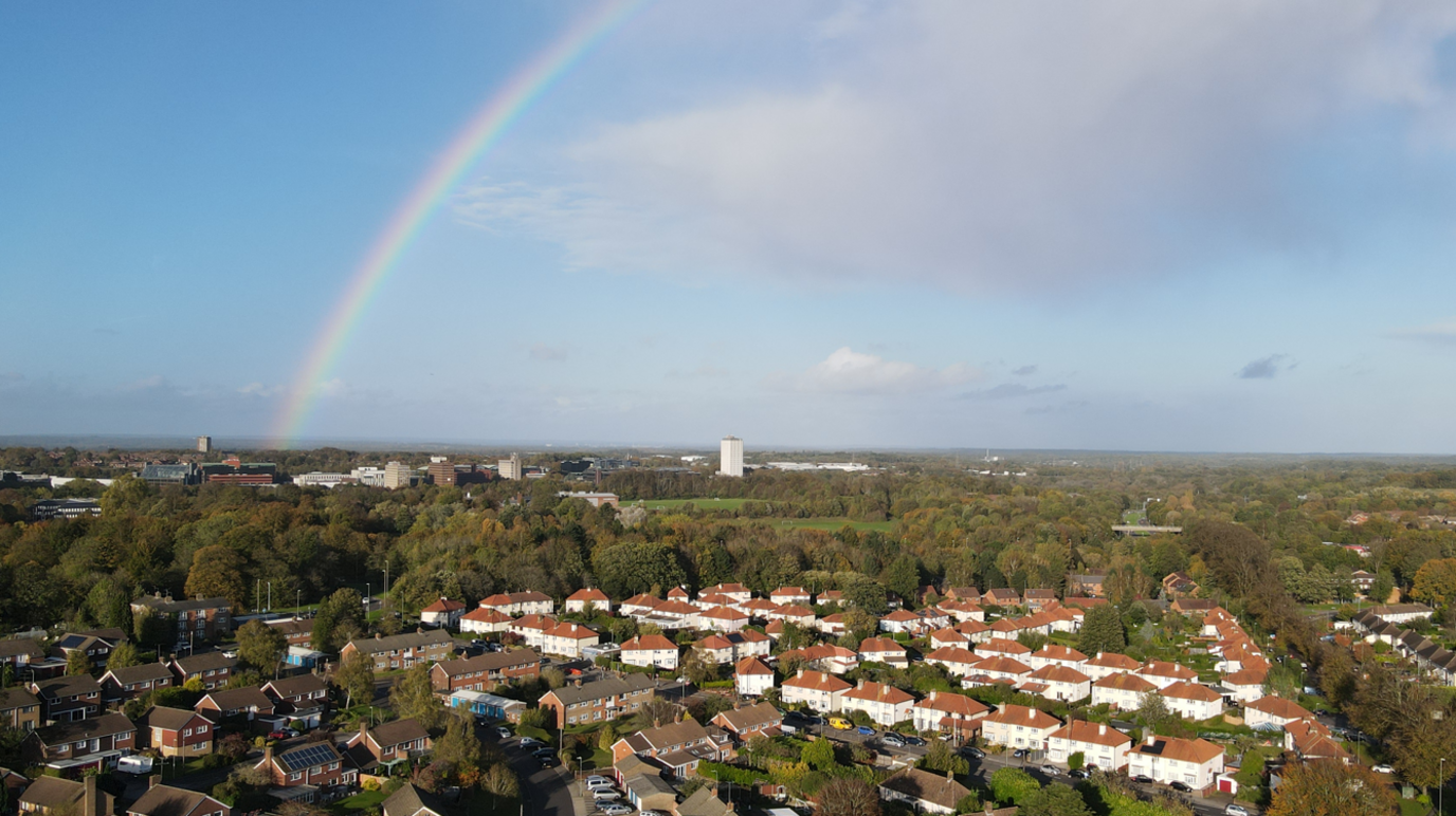 Aerial shot of Basingstoke, a built-up area with lots of houses. There is a rainbow in the sky.