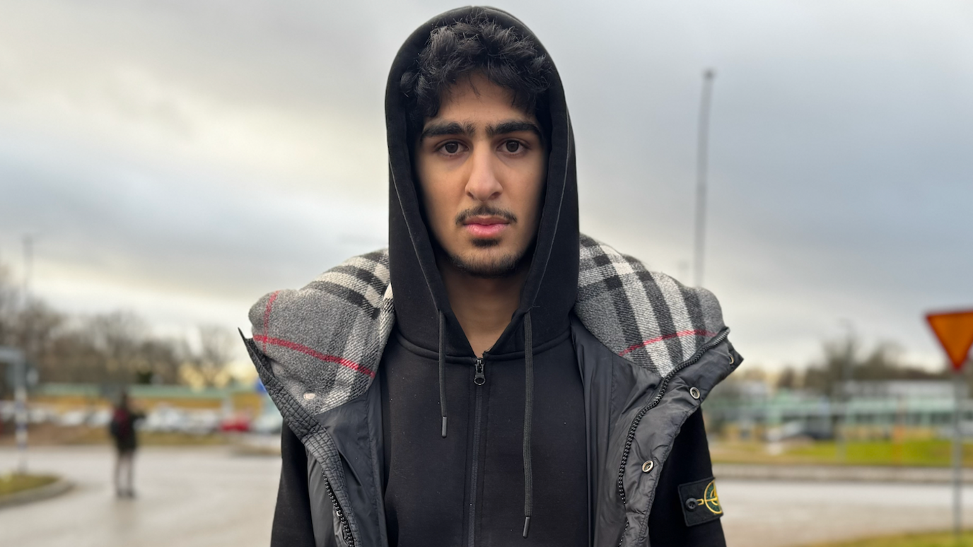 Man with moustache wears black sweatshirt and grey puffy vest while facing camera