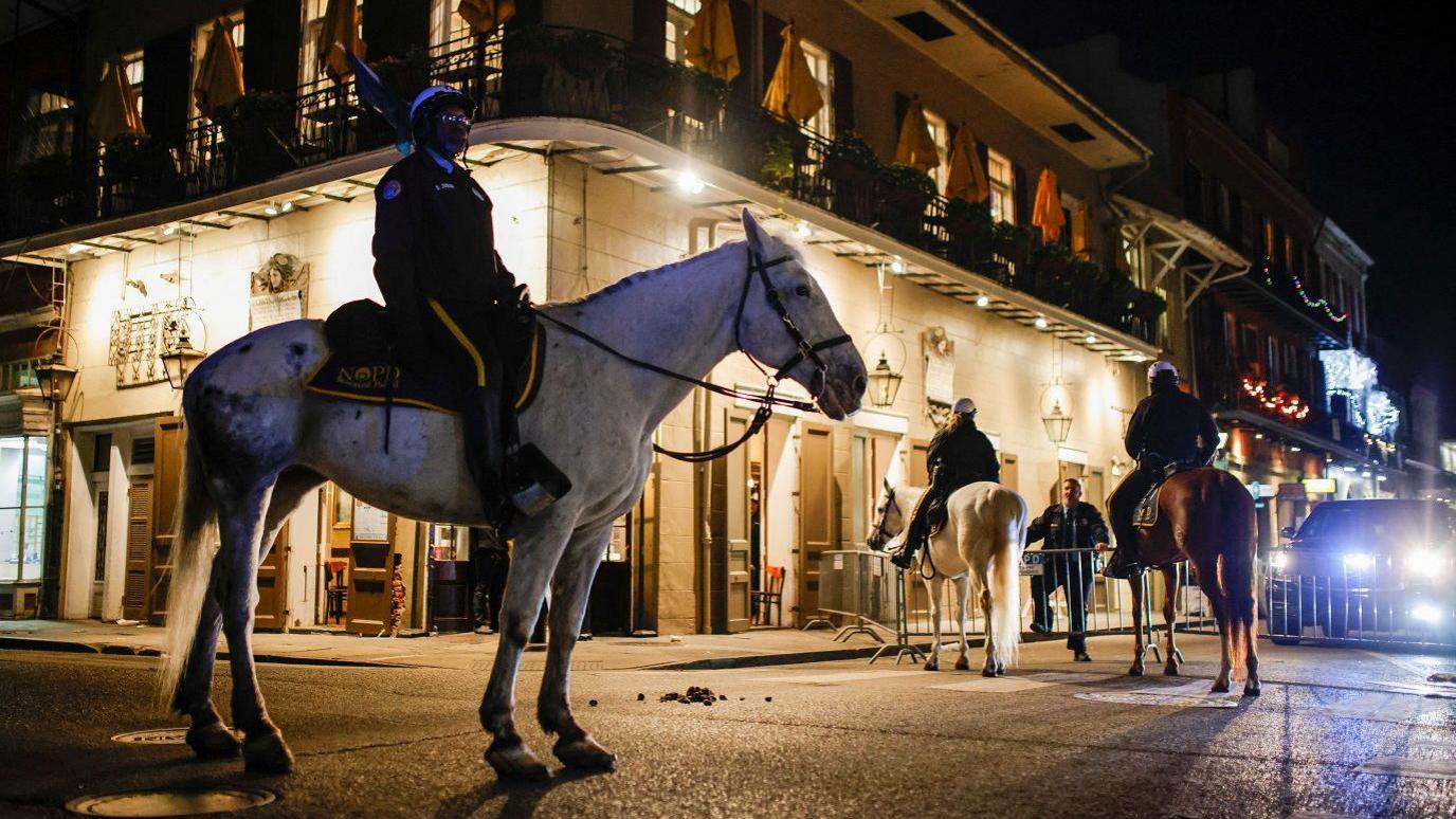 Police officers sit on horses near the site where people were killed by a man driving a truck in an attack during New Year's celebrations, in New Orleans