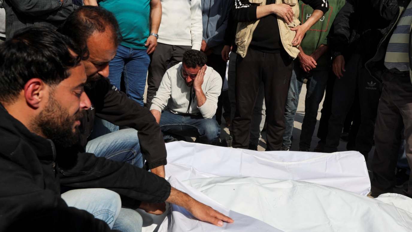 Mourners cry over the covered bodies of Palestinians killed in Israeli strikes, at Al-Aqsa Martyrs hospital, in Deir Al-Balah on March 18, 2025