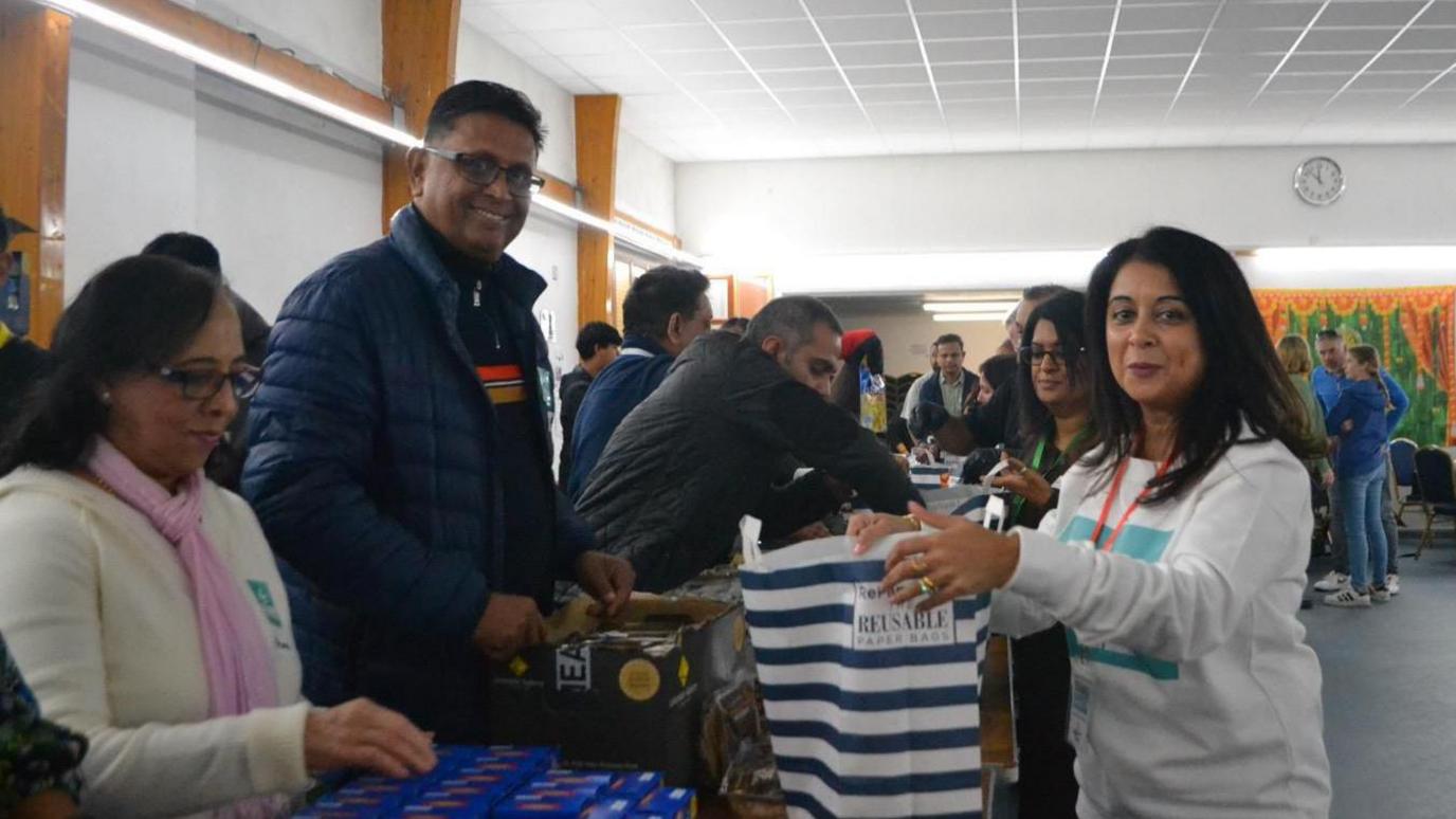 People packaging food hampers on a table.