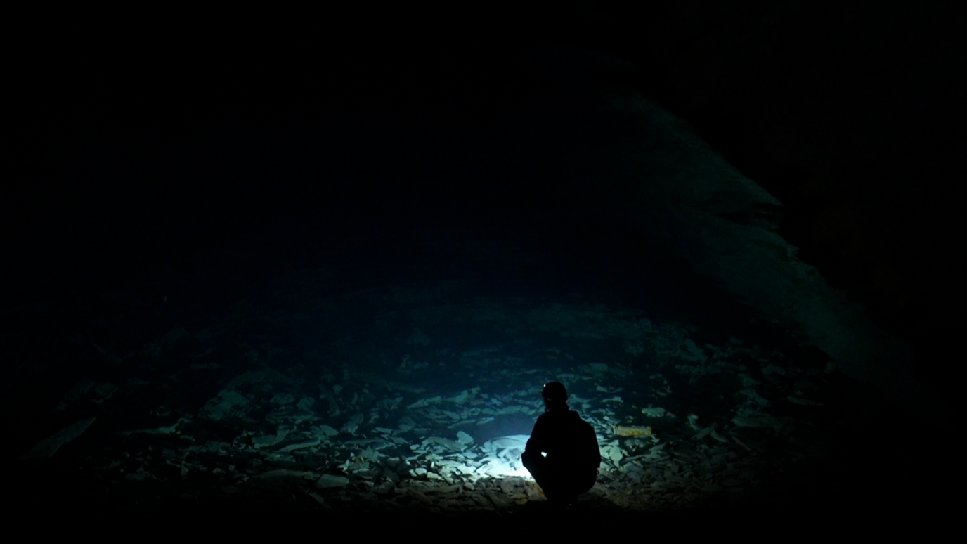 Flooded part of the mine - with member of staff silhouetted against the water in a chamber