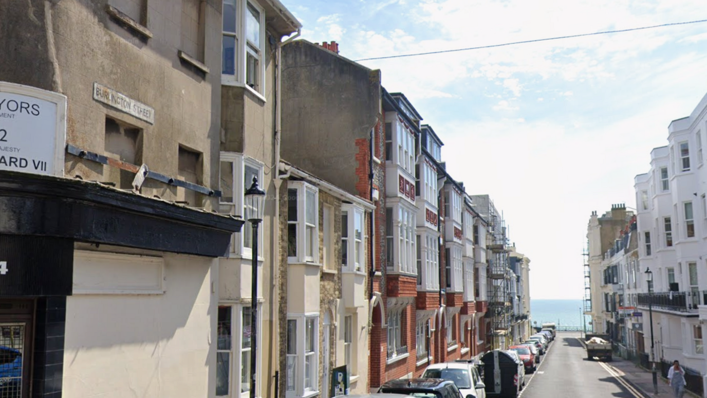 A view of Burlington Street in Kemptown, Brighton, a narrow row of three-storey Regency terrace houses leading to the seafront.
