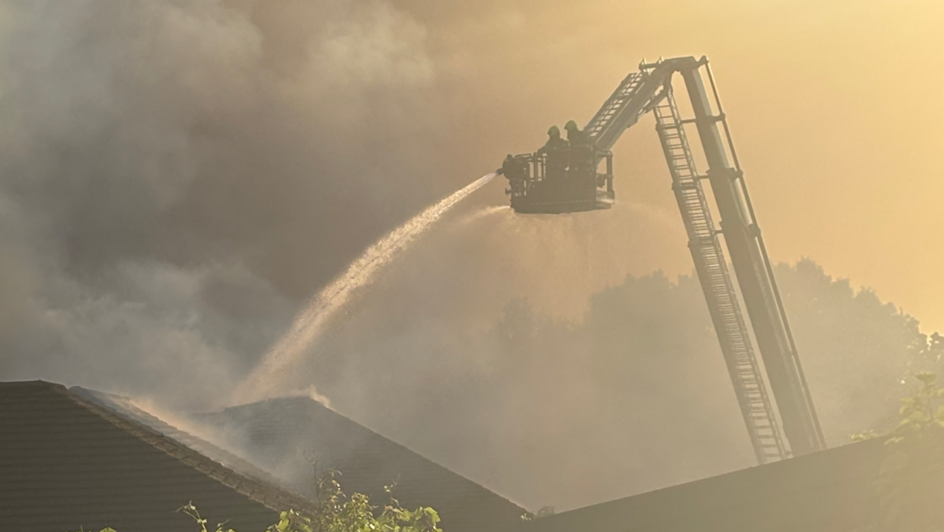 Firefighters using an aerial platform to tackle the blaze with a lot of smoke obscuring the picture.
