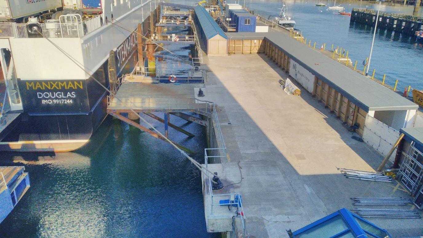 A concreted area of quayside next to the Manxman ferry, which is docked in the harbour.