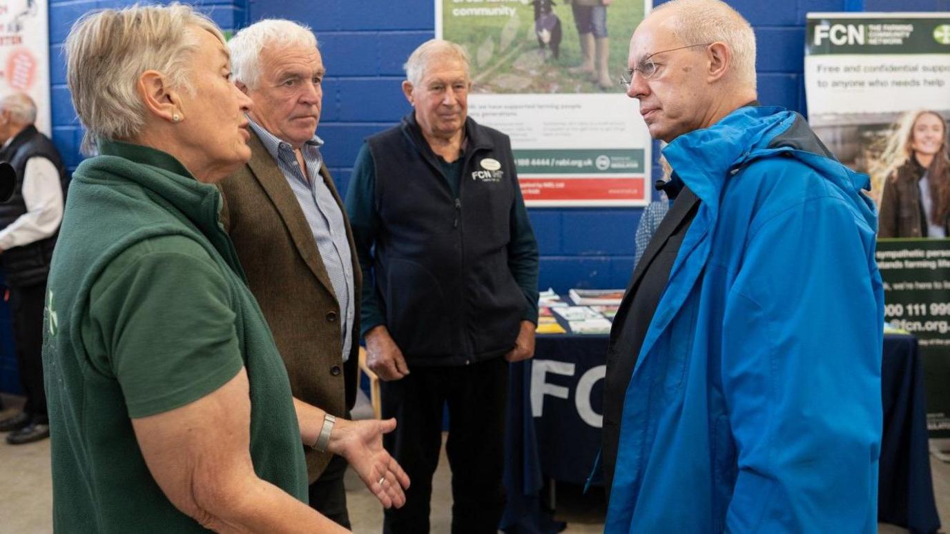 The archbishop (right) talking with Maureen Trott (left) at the market. He is wearing a blue coat and she is in a green top.