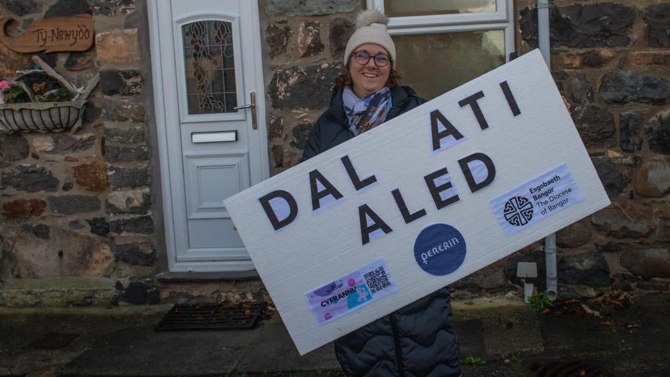 Dynes gyda arwydd 'Dal Ati Aled'