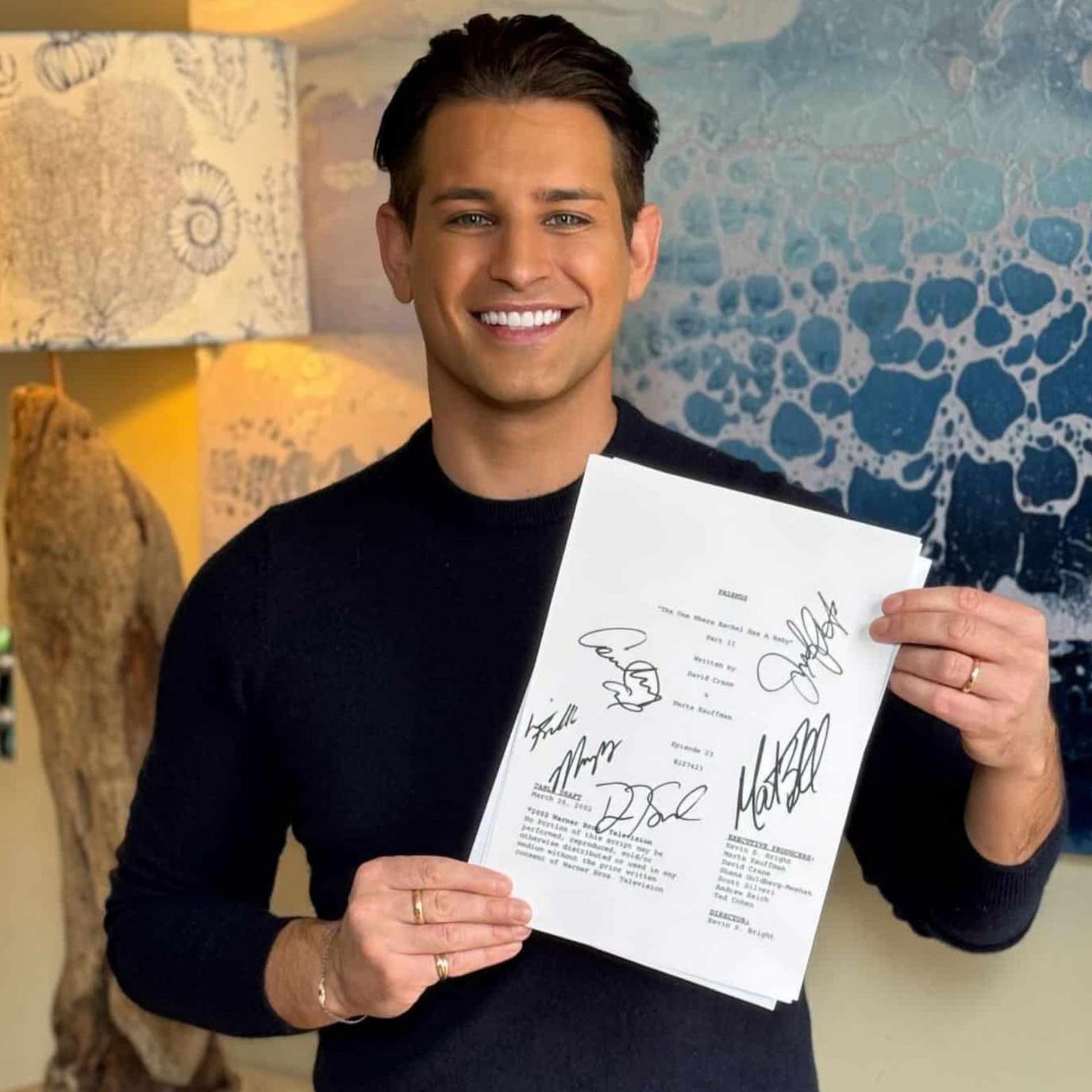 Ollie Locke is smilingand holding the script