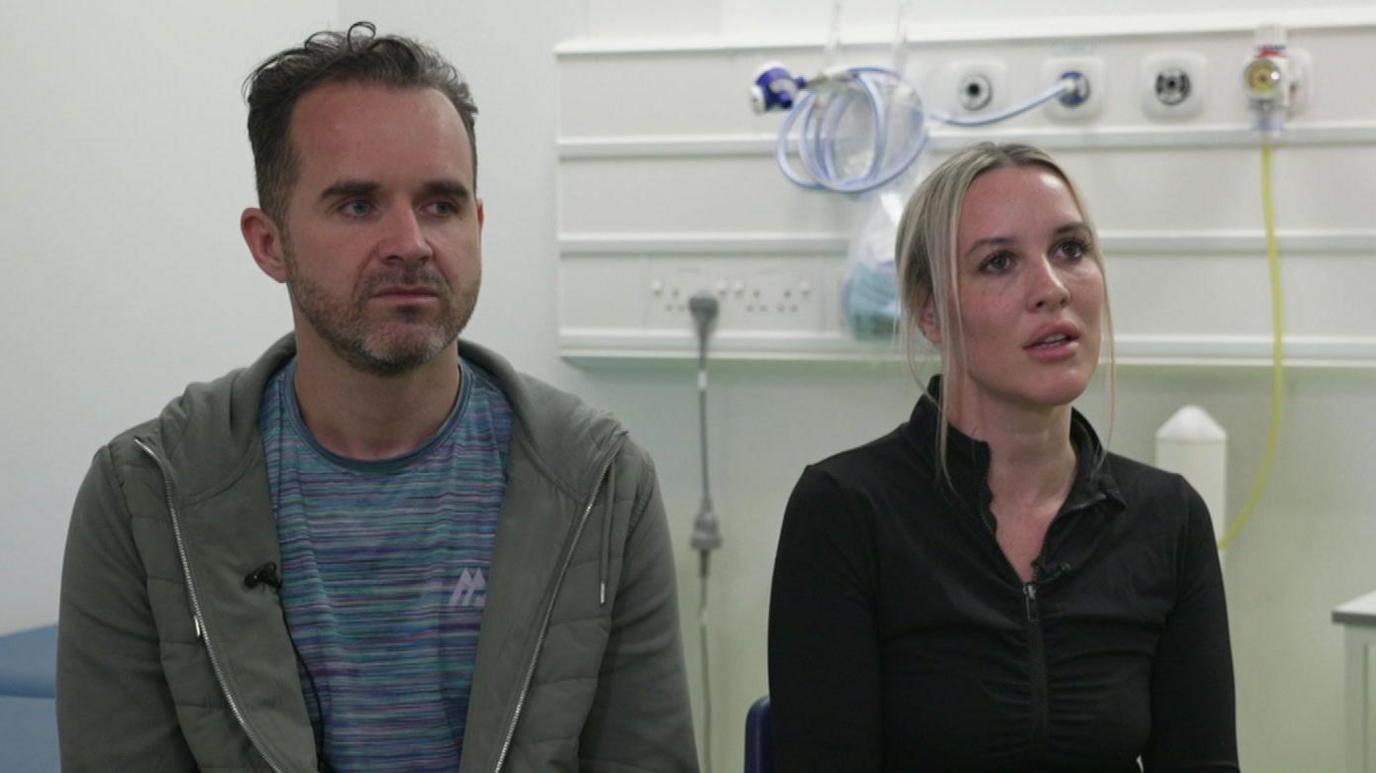 Liam (left) and Natasha sit in a hospital room