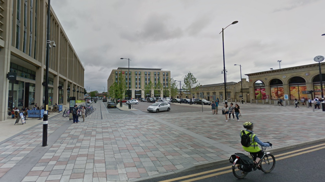 Station Square, Cambridge with parked cars, people and bicycles