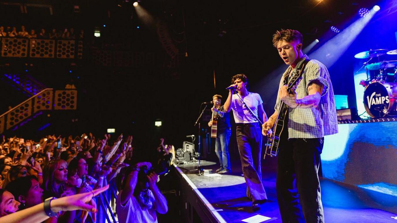 Members of the band The Vamps perform on stage at the O2 Academy in Bristol with the crowd staring up at them