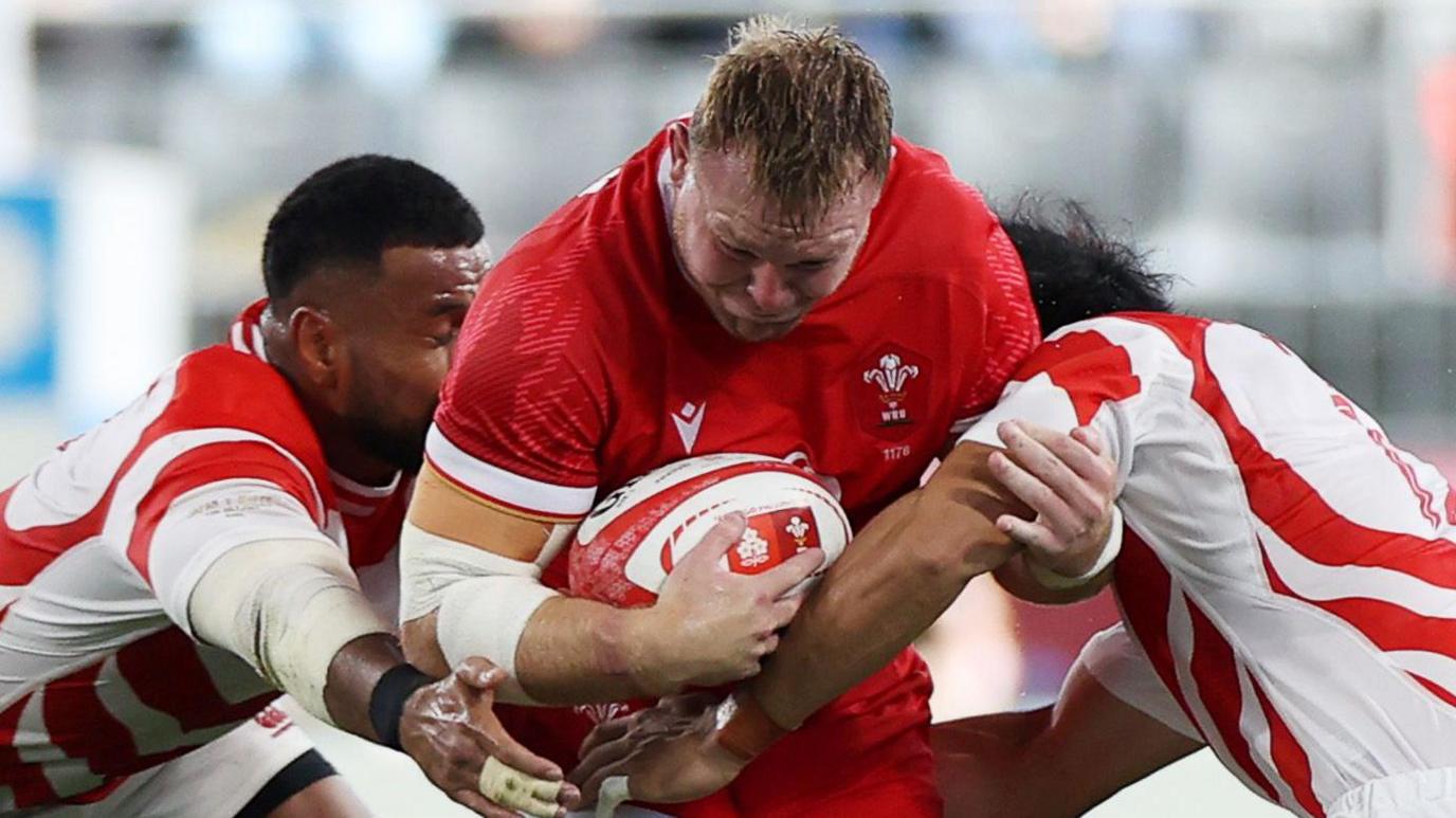 Wales hooker Dewi Lake attacks the Japan defence with two tacklers trying to stop him