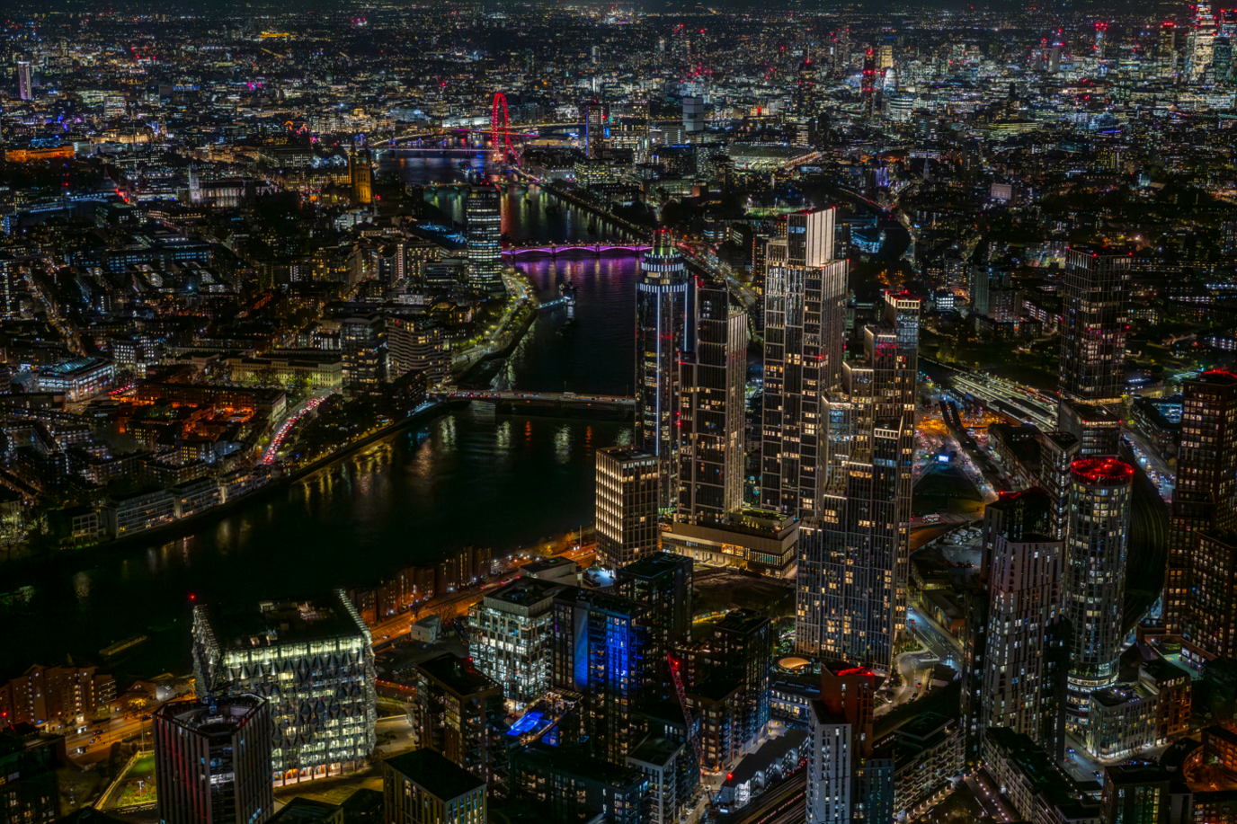 Aerial photograph taken at night showing tower blocks of Nine Elms and the American Embassy with the Thames flowing past them and the buildings of the rest of London behind them